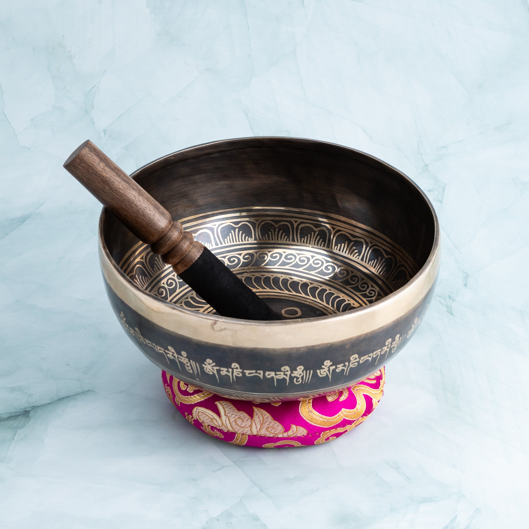 Singing bowl with wooden mallet and pink cushion