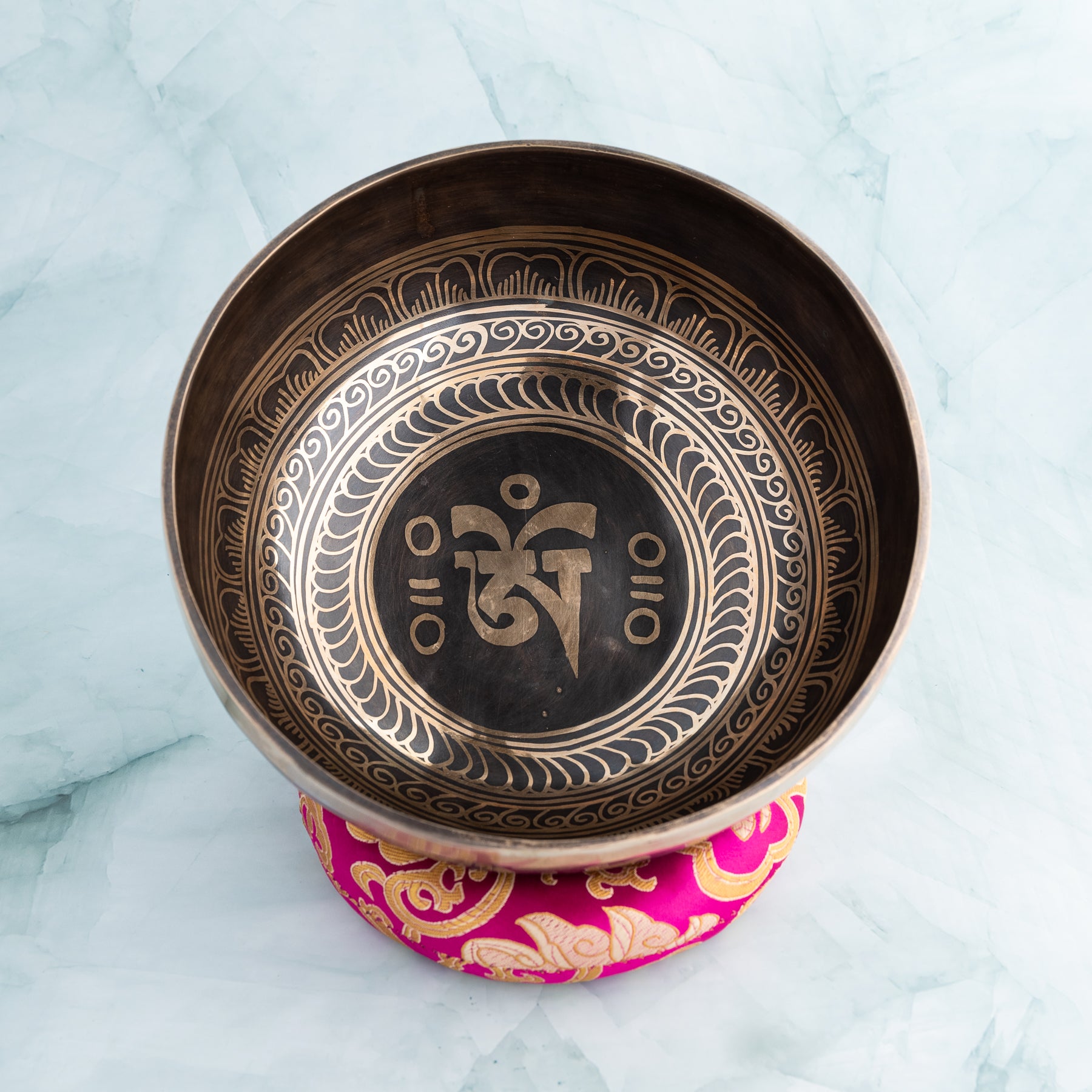 Inside of a singing bowl on a pink cushion