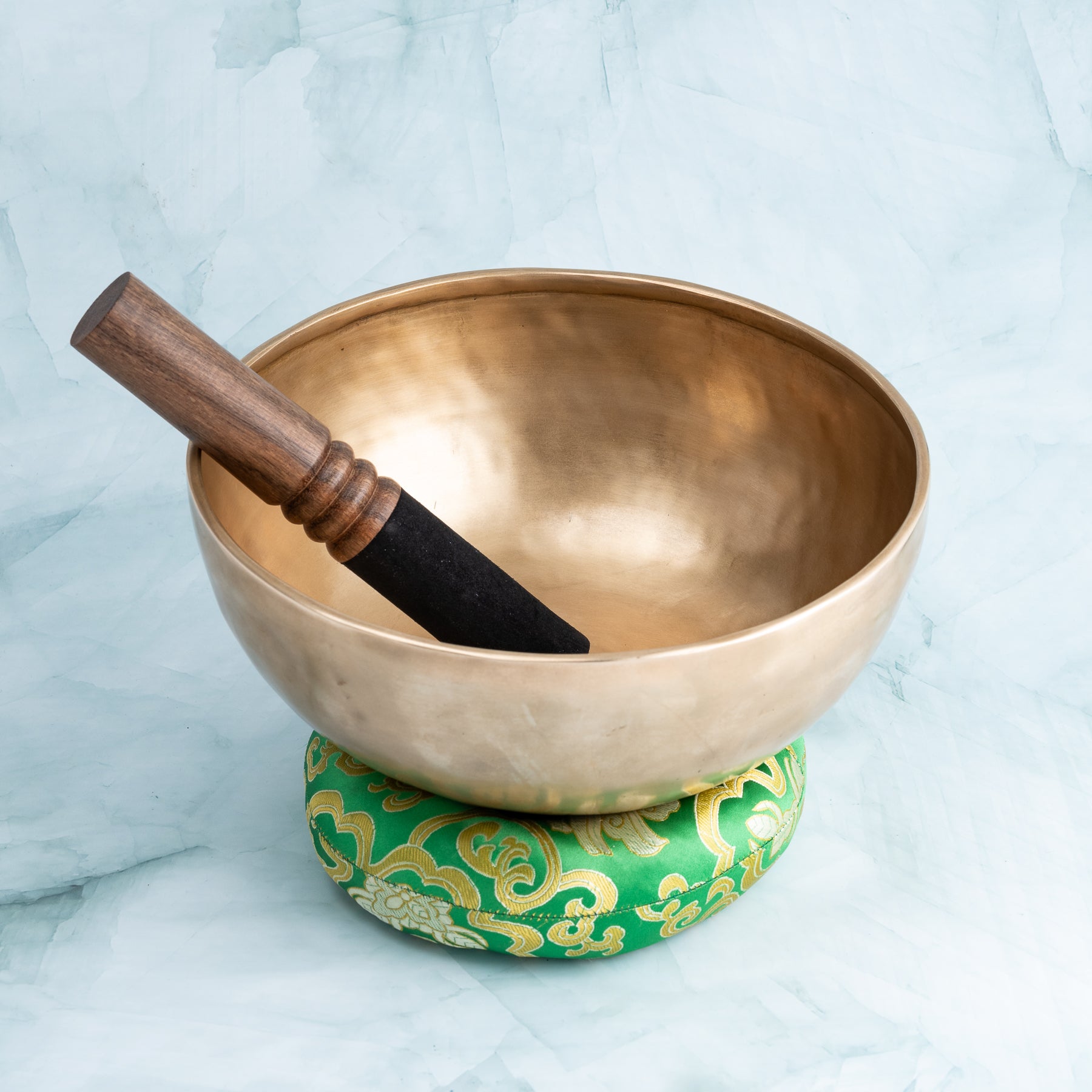 Bronze singing bowl, mallet and green cushion